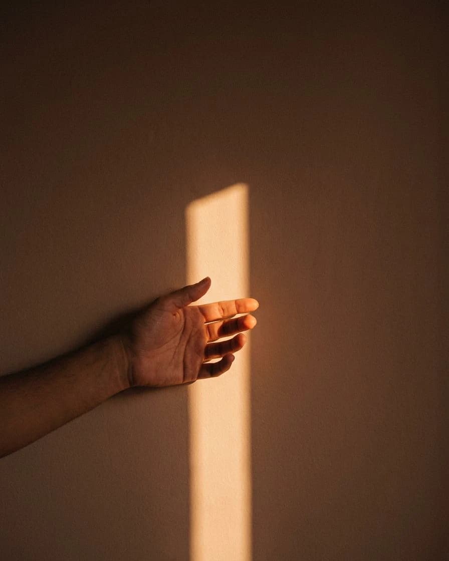 Uma mão aberta tocando a luz que entra por uma janela